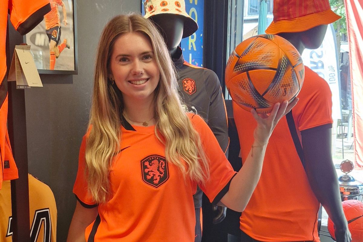 Meisje in een oranje voetbal shirt met een oranje bal in haar handen